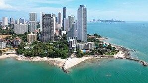 Un paisaje urbano costero con edificios altos, una playa y un litoral rocoso.