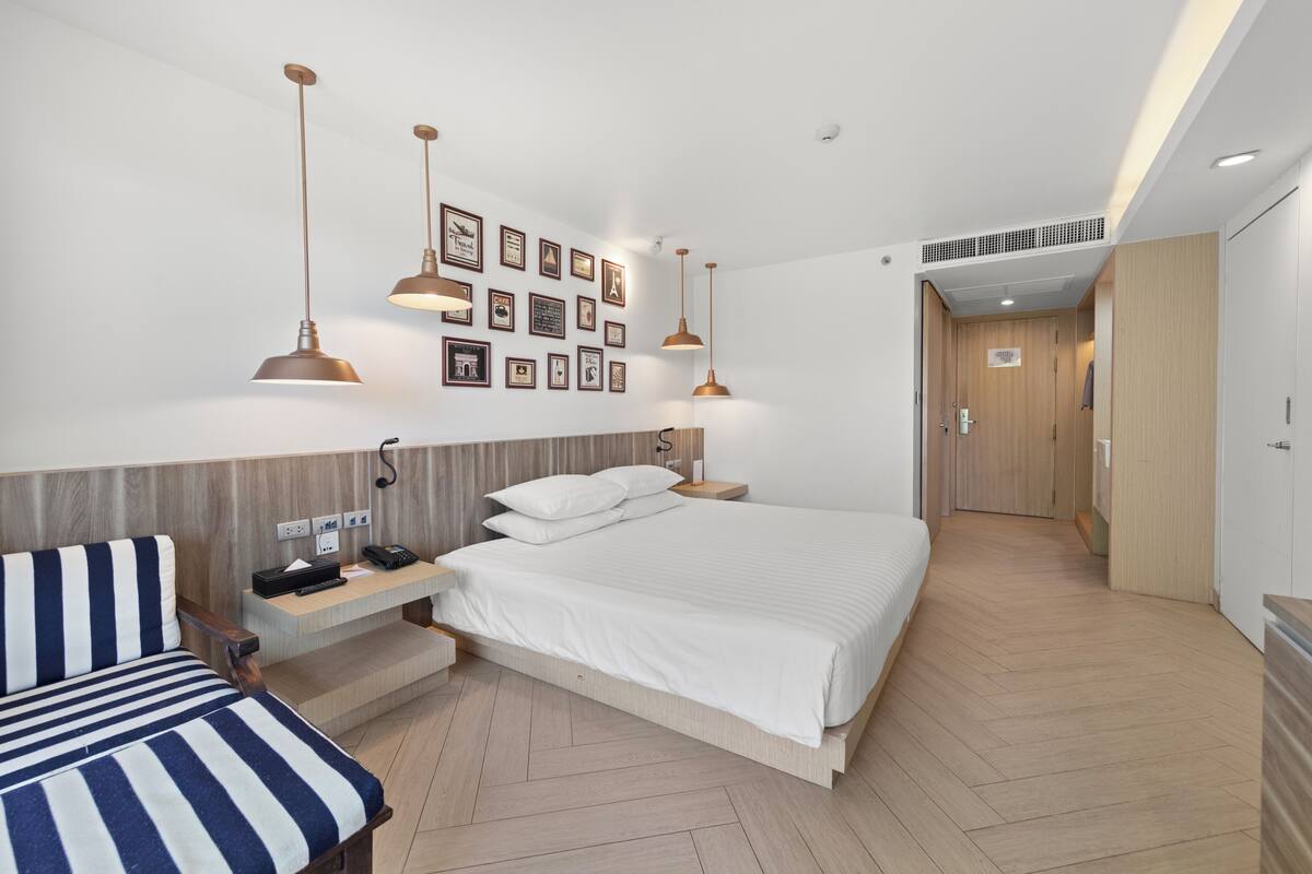 Een moderne hotelkamer met een groot bed, nachtkastjes, een bureau en een stoel. Er zijn wandlampen en een galerij met ingelijste foto's.