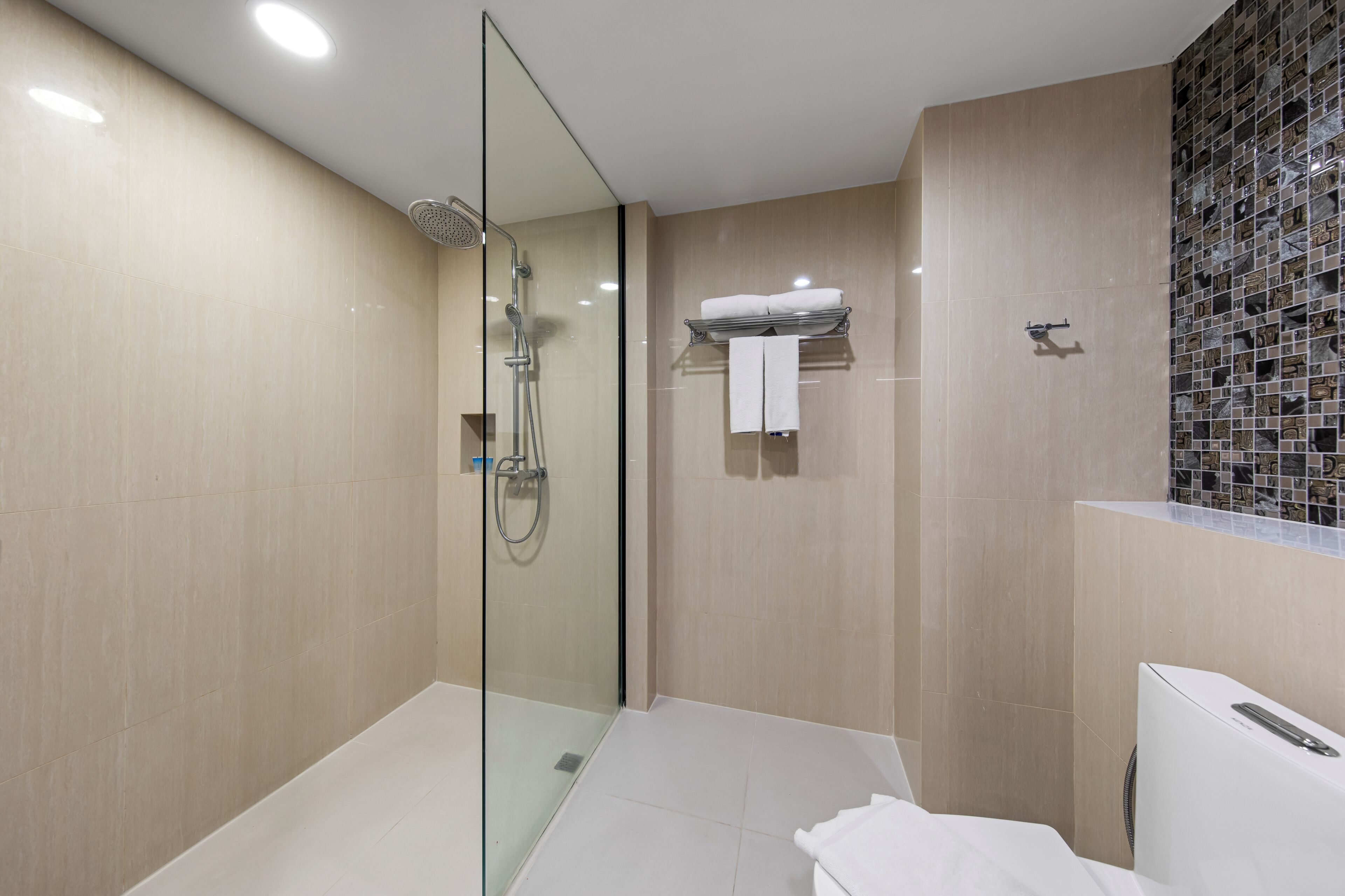 Un baño moderno con ducha envuelta en cristal, un lavabo blanco y un perchero para toallas.