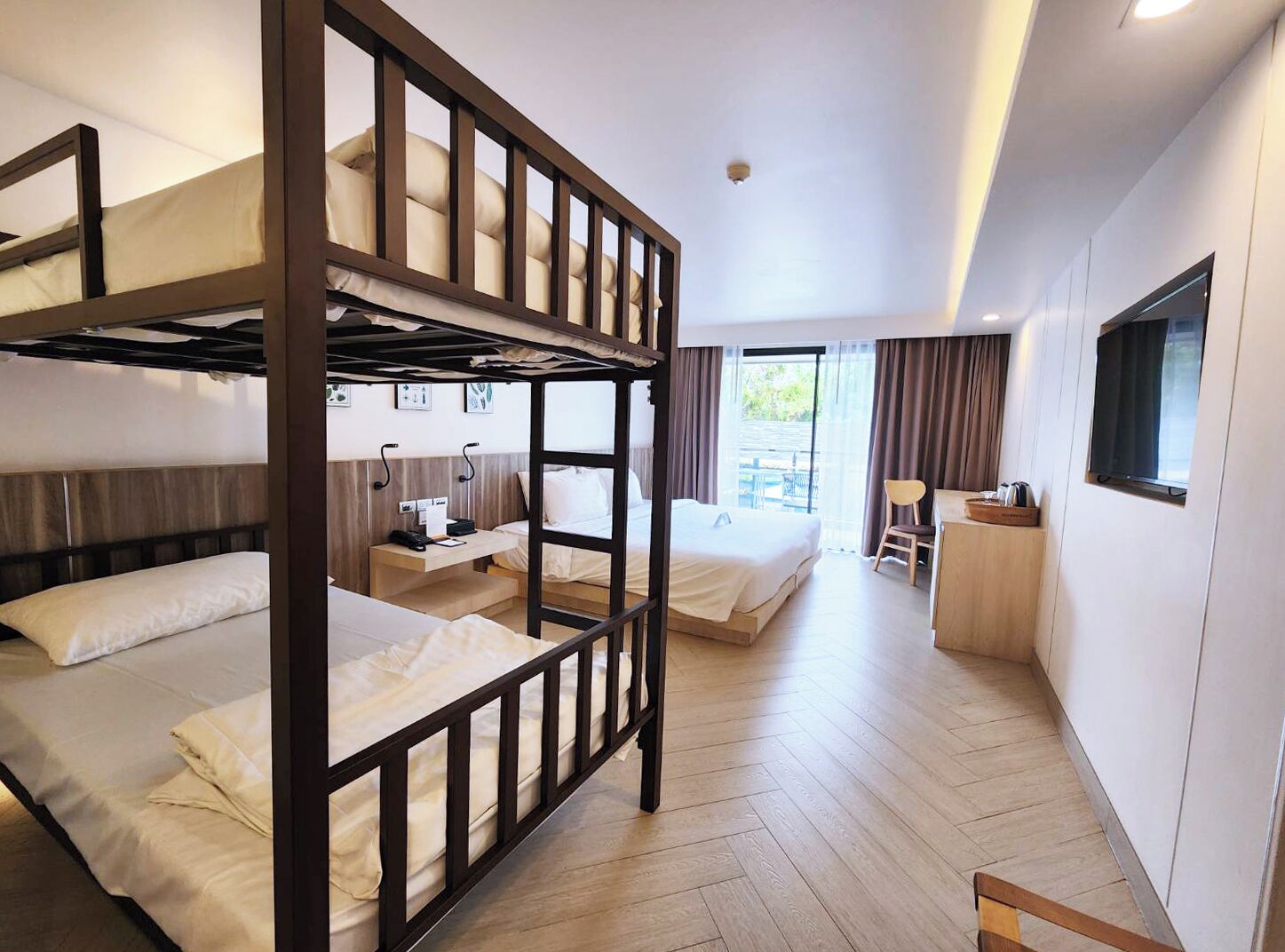 A hotel room with bunk beds, a desk, a chair, and a television.