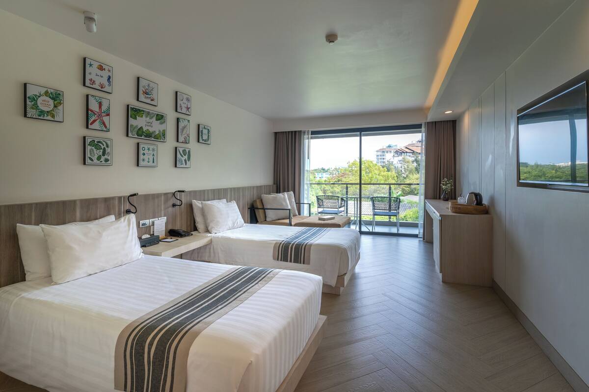 Een hotelkamer met twee bedden, een balkon en een groot raam.