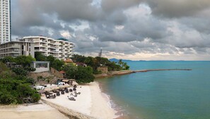 Un hotel frente al mar con varios pisos, una playa de arena y un mar tranquilo.