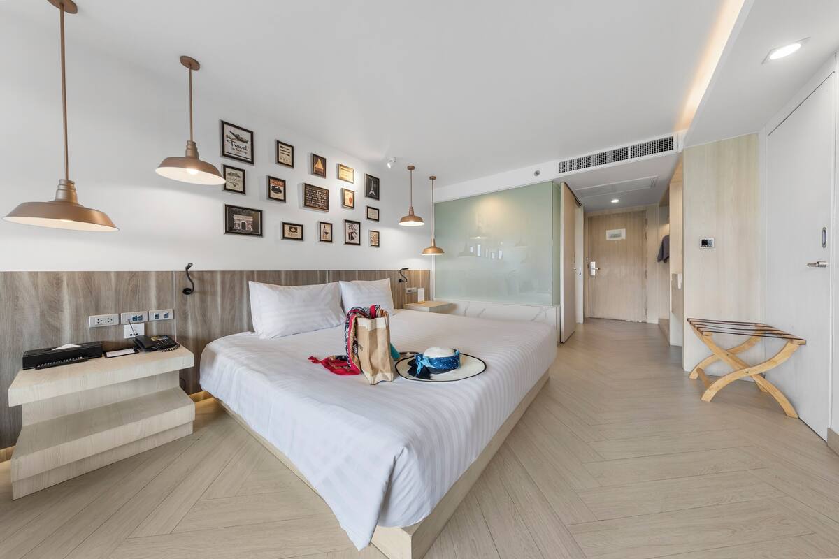 Een moderne hotelkamer met een groot bed, nachtkastje en kunstwerk aan de muur.
