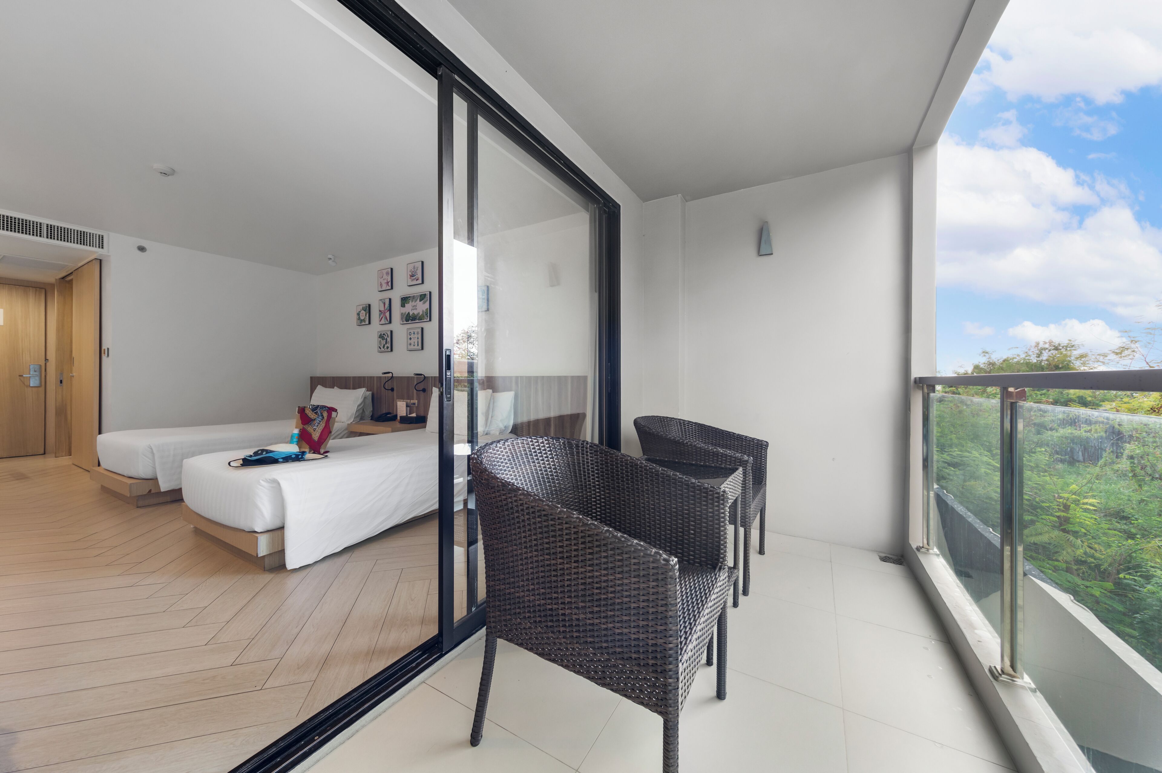 A modern bedroom with a bed, a desk, and a balcony with wicker chairs.
