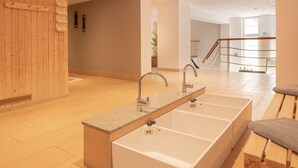 A modern bathroom with a long, rectangular sink and a wooden wall. - Waldhotel Berghof (Luisenthal)