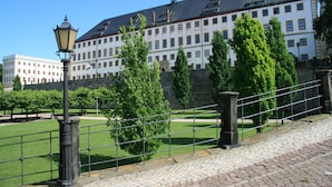 A historic building with a large courtyard, a lamp post, and a metal fence. - Waldhotel Berghof (Luisenthal)