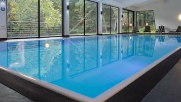 Una piscina techada, sillones reclinables de piscina