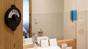A bathroom with a wooden door, a white sink, and a mirror.