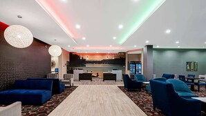 A modern lobby with a reception desk, seating area, and a view of a bridge. - La Quinta Inn & Suites by Wyndham Tuscaloosa University (Tuscaloosa)