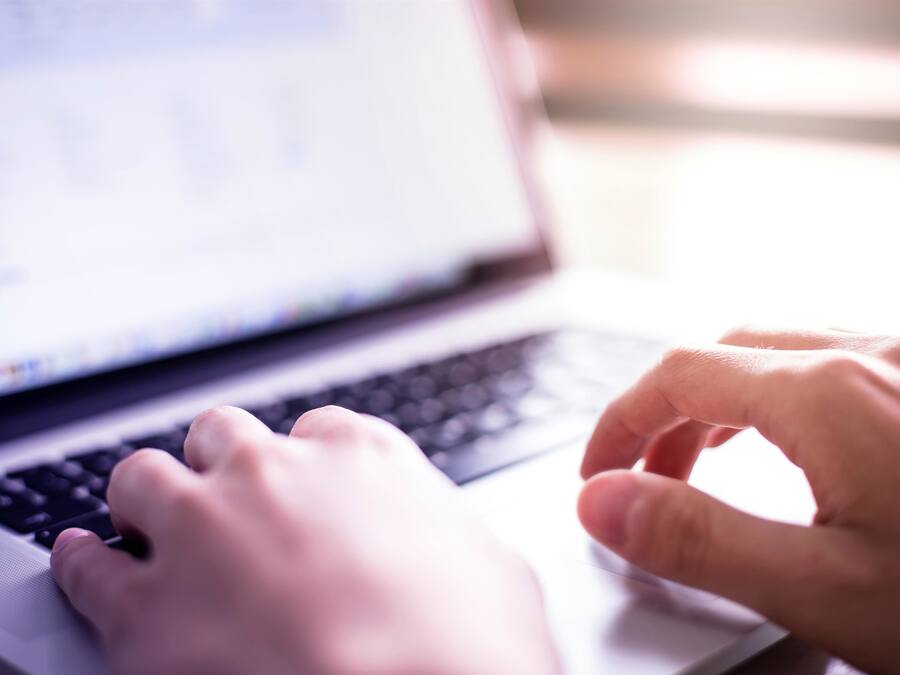 Gros plan sur des mains tapant sur le clavier d’un ordinateur portable.