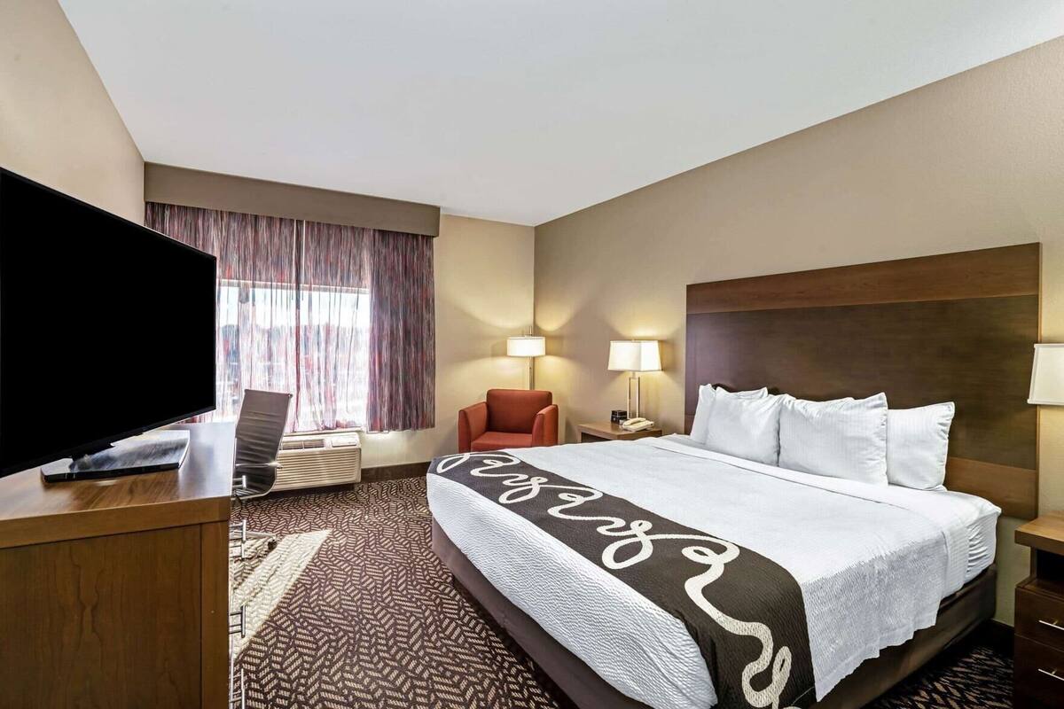 Une chambre d’hôtel équipée d’un lit, d’une télévision, d’un bureau, d’une chaise et de deux lampes de chevet.