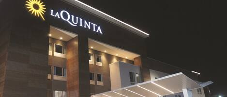 Un hotel llamado La Quinta, con una fachada moderna, ventanas amplias y una entrada bien iluminada.