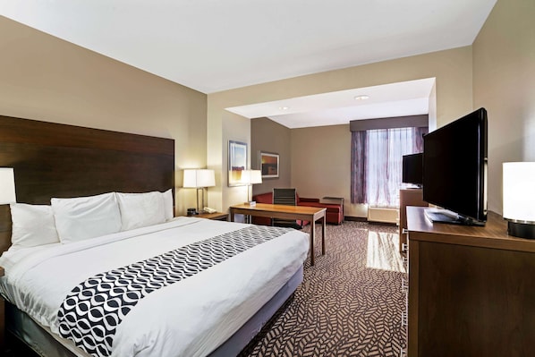 Habitación de hotel con una cama grande, un escritorio, un televisor y una ventana con cortinas.