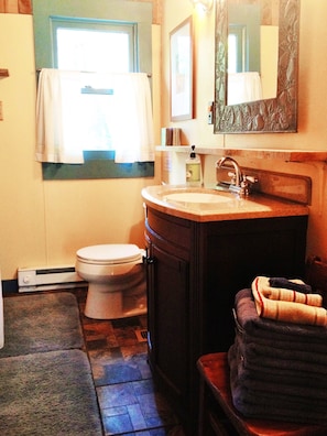A bathroom with a toilet, sink, and mirror. - DeHart Cabin (Lexington)