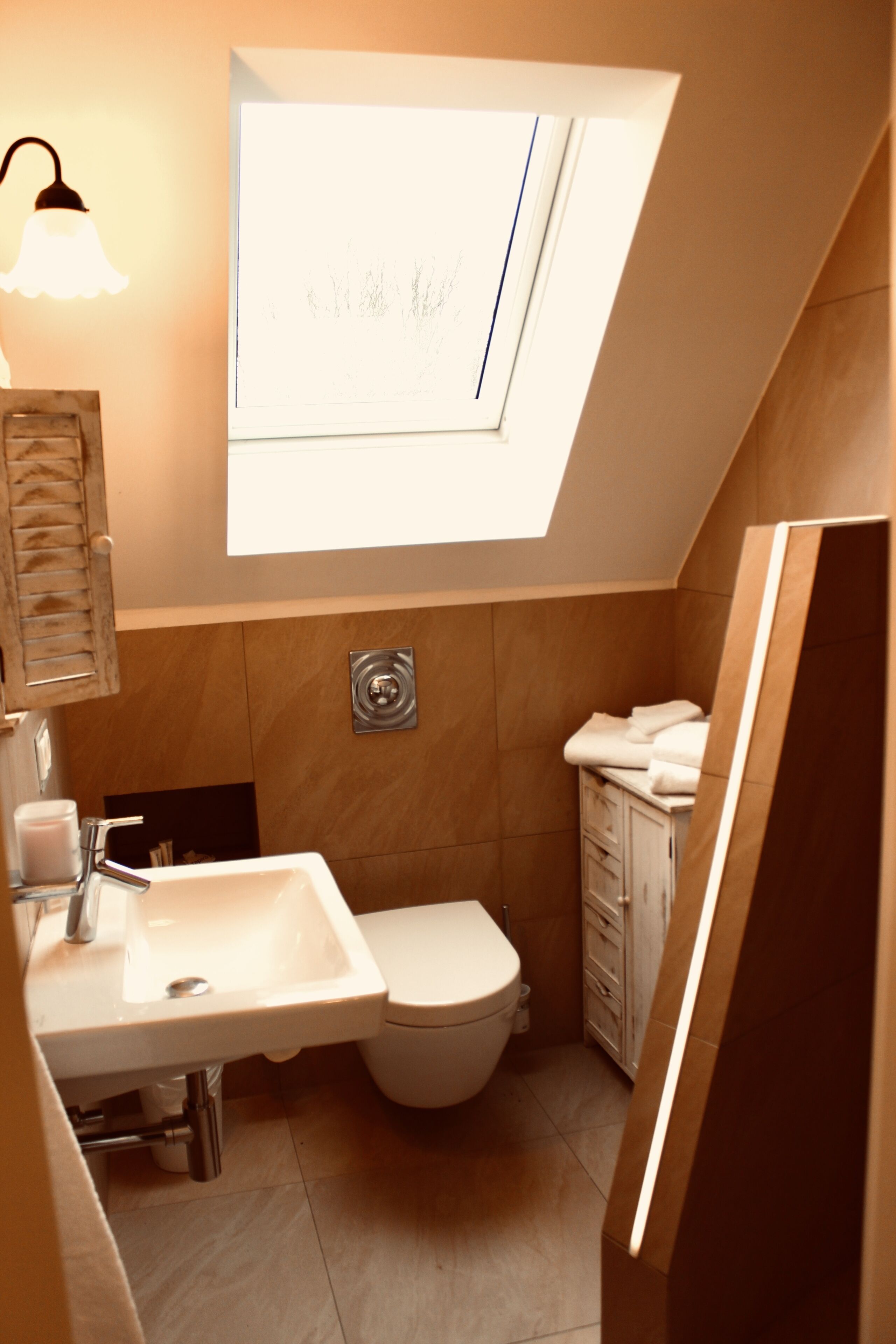 A compact bathroom with a skylight, a sink, and a toilet.