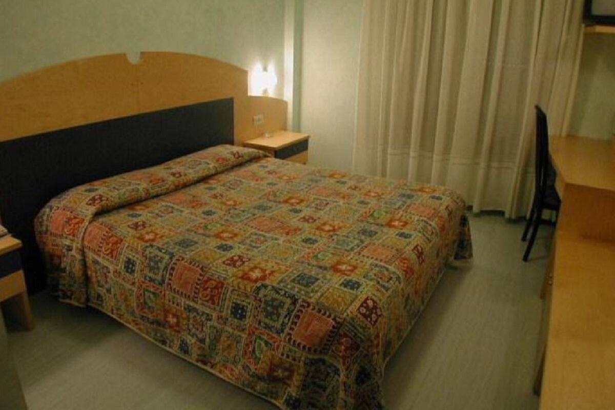 Une chambre d’hôtel avec un lit, une table de chevet, un bureau et une chaise.