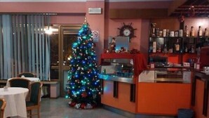 A room with a Christmas tree, a dining area with chairs and a table, and a bar area with shelves of bottles. - Hotel Palladio (San Fior di Sopra)