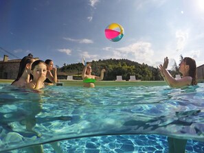 A swimming pool with clear water, a beach ball, and people playing. - Le Moulin de Sournia - Gites (Sournia)