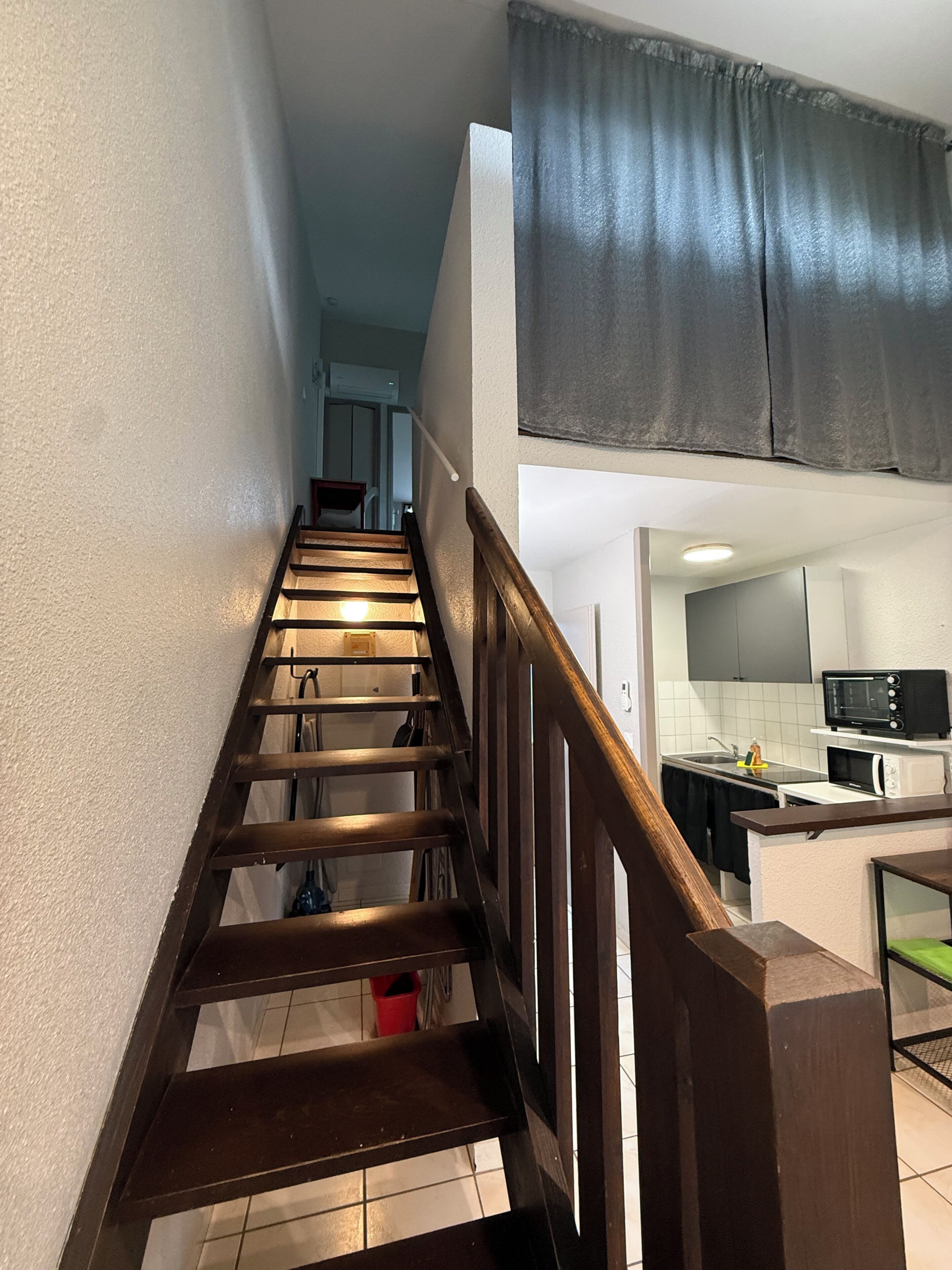 A staircase leading to a kitchen with a microwave and a sink.