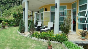 A modern house with a curved roof, large windows, and a patio with outdoor furniture.