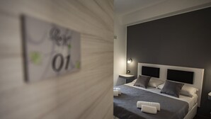 Une chambre d’hôtel moderne avec un grand lit, deux tables de chevet et une tête de lit sombre.