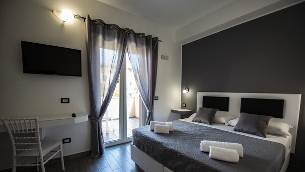 Une chambre moderne avec un grand lit, un bureau et un téléviseur fixé au mur.
