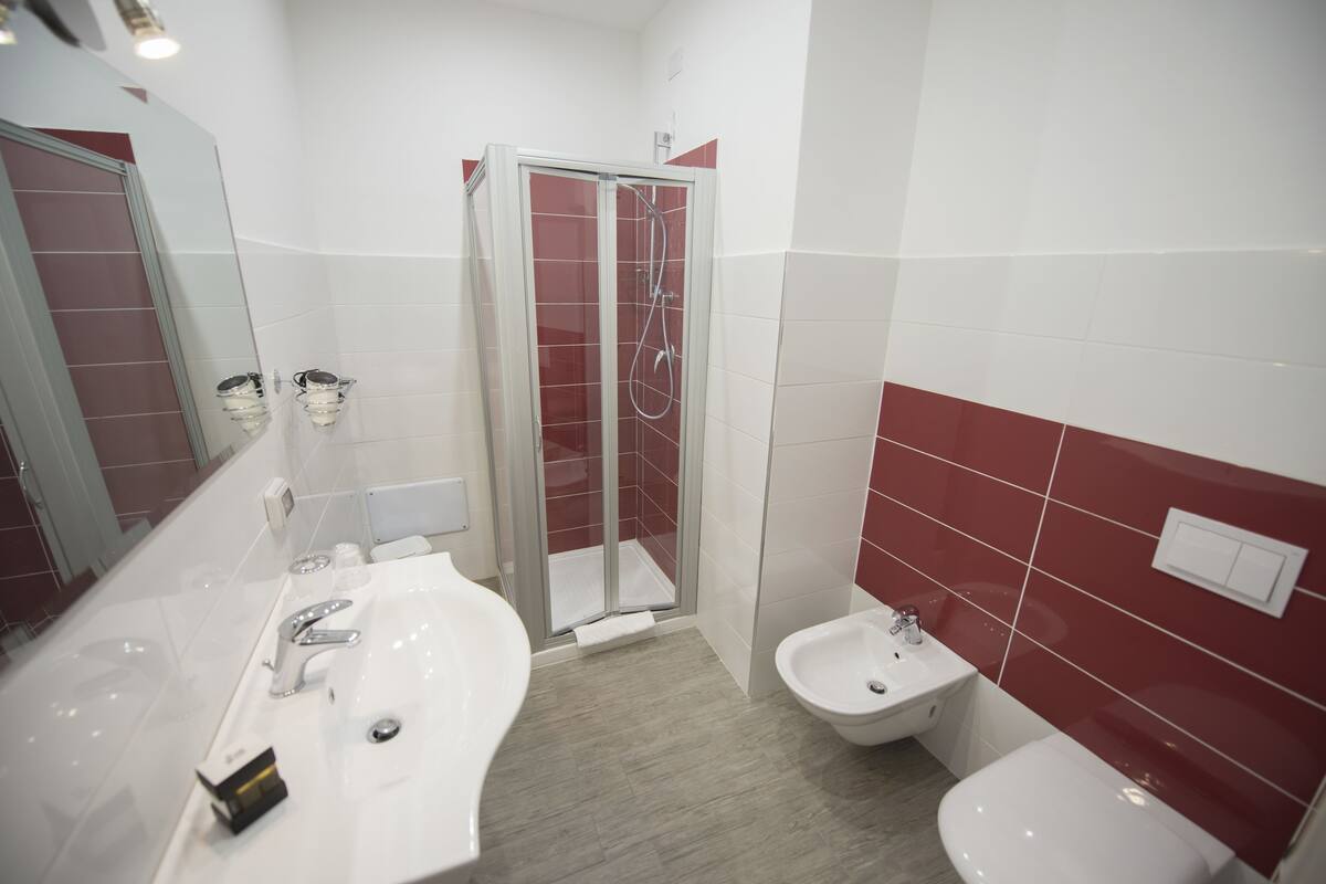 Un baño moderno con ducha de vidrio, lavamanos doble y bidé.