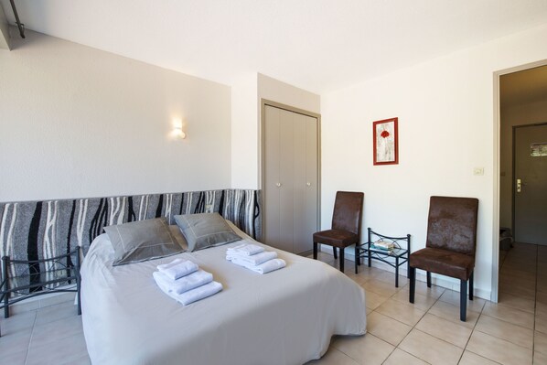 A hotel room with a bed, two chairs, a small table, and a door. - Le Moulin de Sournia (Sournia)