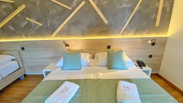 A hotel room with a large bed, two pillows, a bedside table with a phone, and a wall with geometric wooden panels.