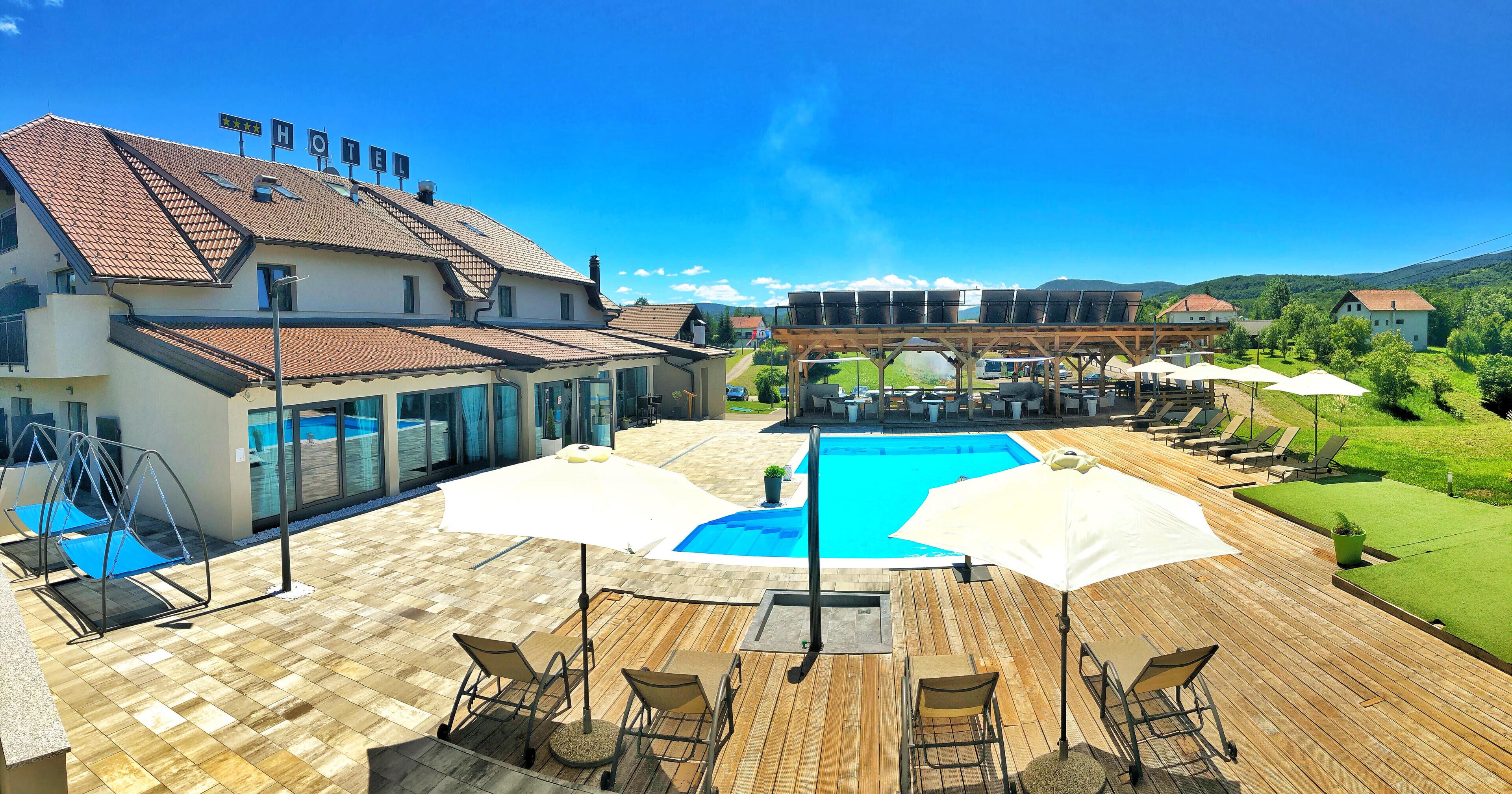 Un hotel con piscina, mobiliario exterior y vistas del paisaje circundante.