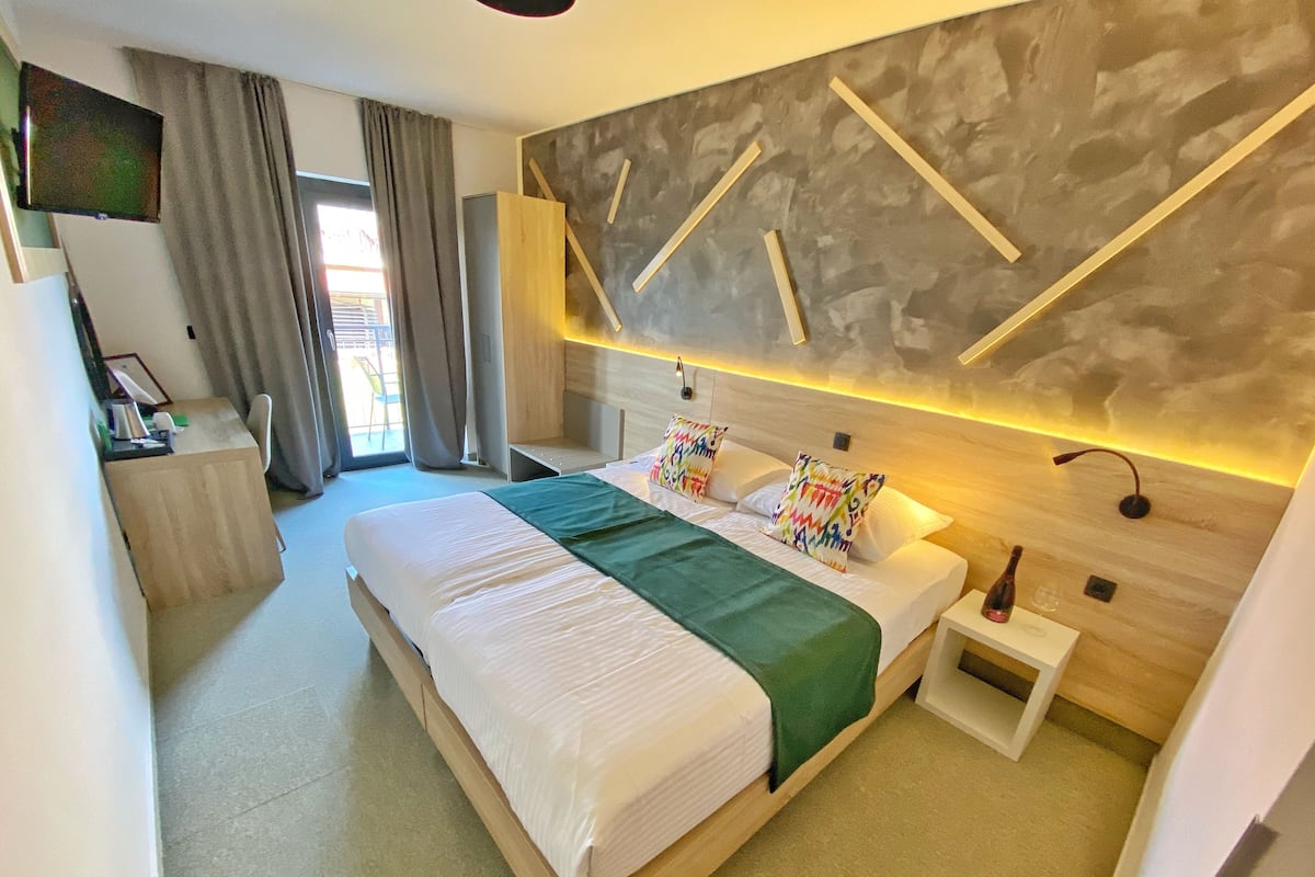 A modern hotel room with a large bed, a desk, and a seating area.