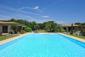 Una piscina al aire libre, sillones reclinables de piscina