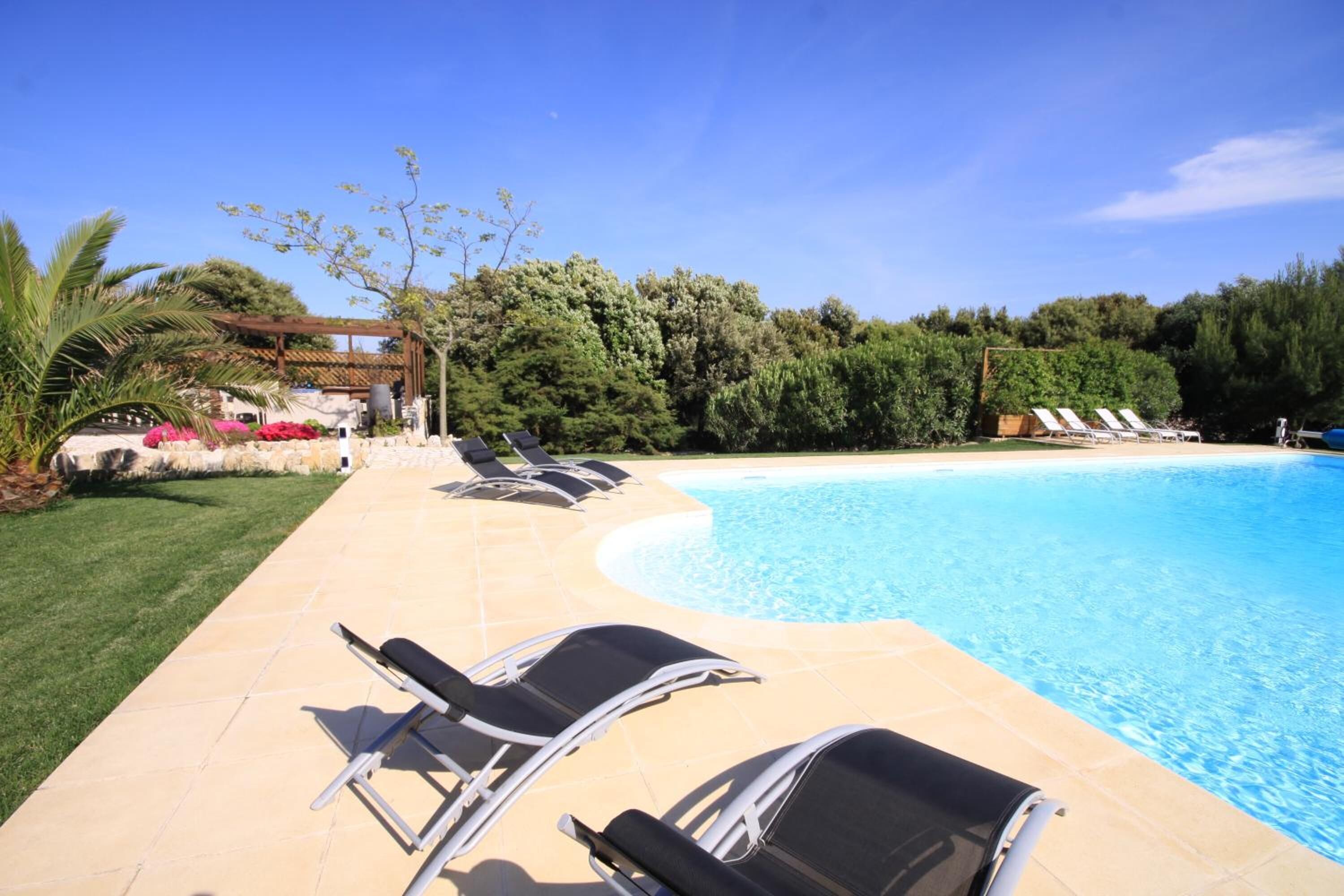 A swimming pool with lounge chairs and a tiled deck.