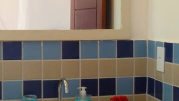 A bathroom with a sink, mirror, and blue-tiled walls.