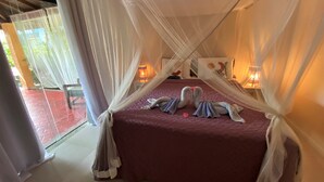 Ein Zimmer mit einem Bett, weißen Vorhängen und zwei Nachttischlampen.