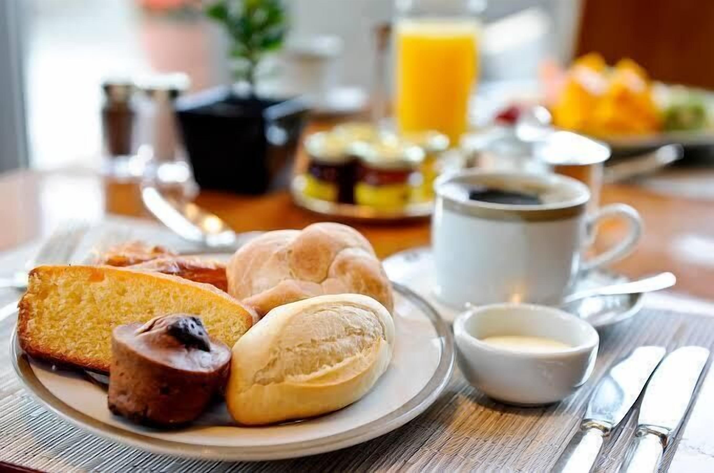 A breakfast setting with bread, pastries, coffee, and juice.
