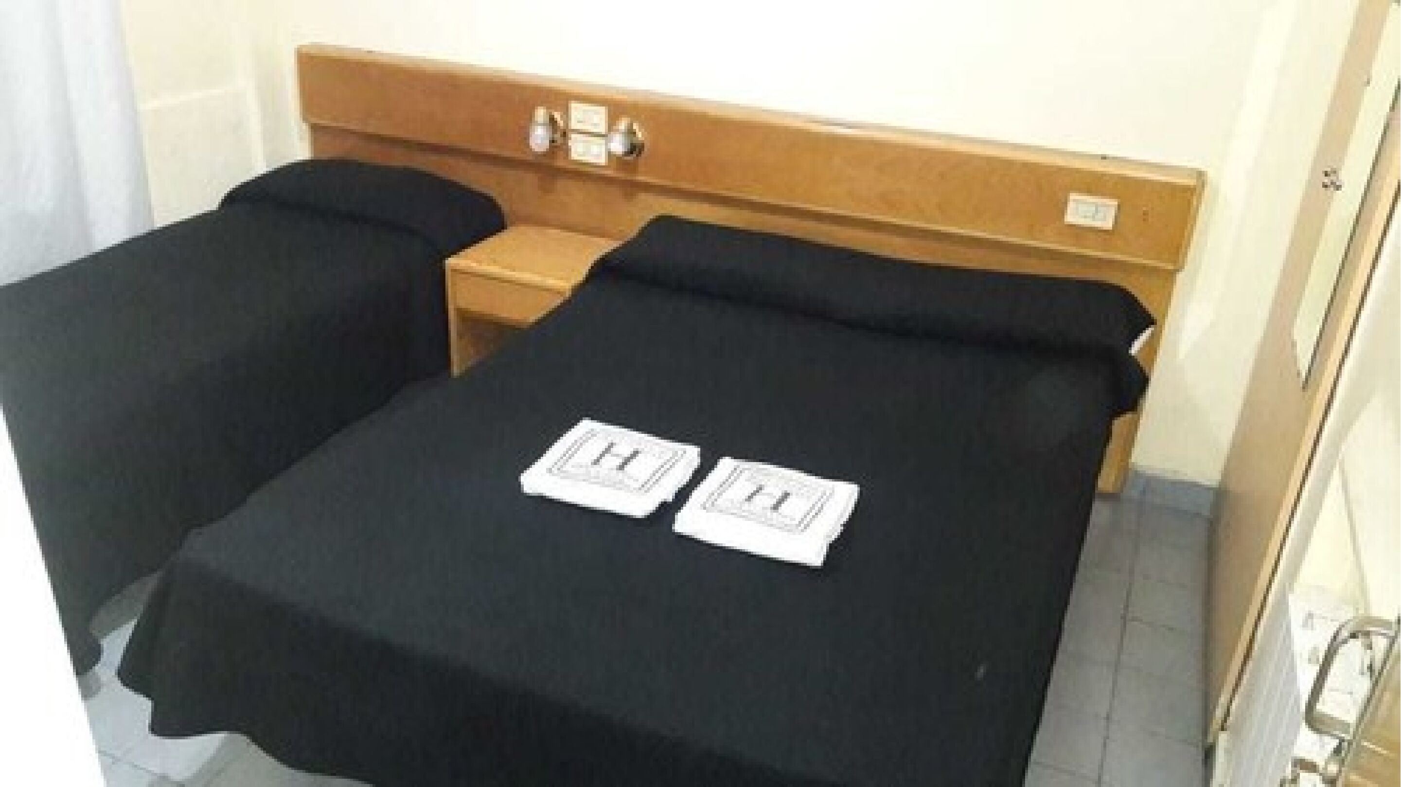 A small hotel room with a single bed and a nightstand.