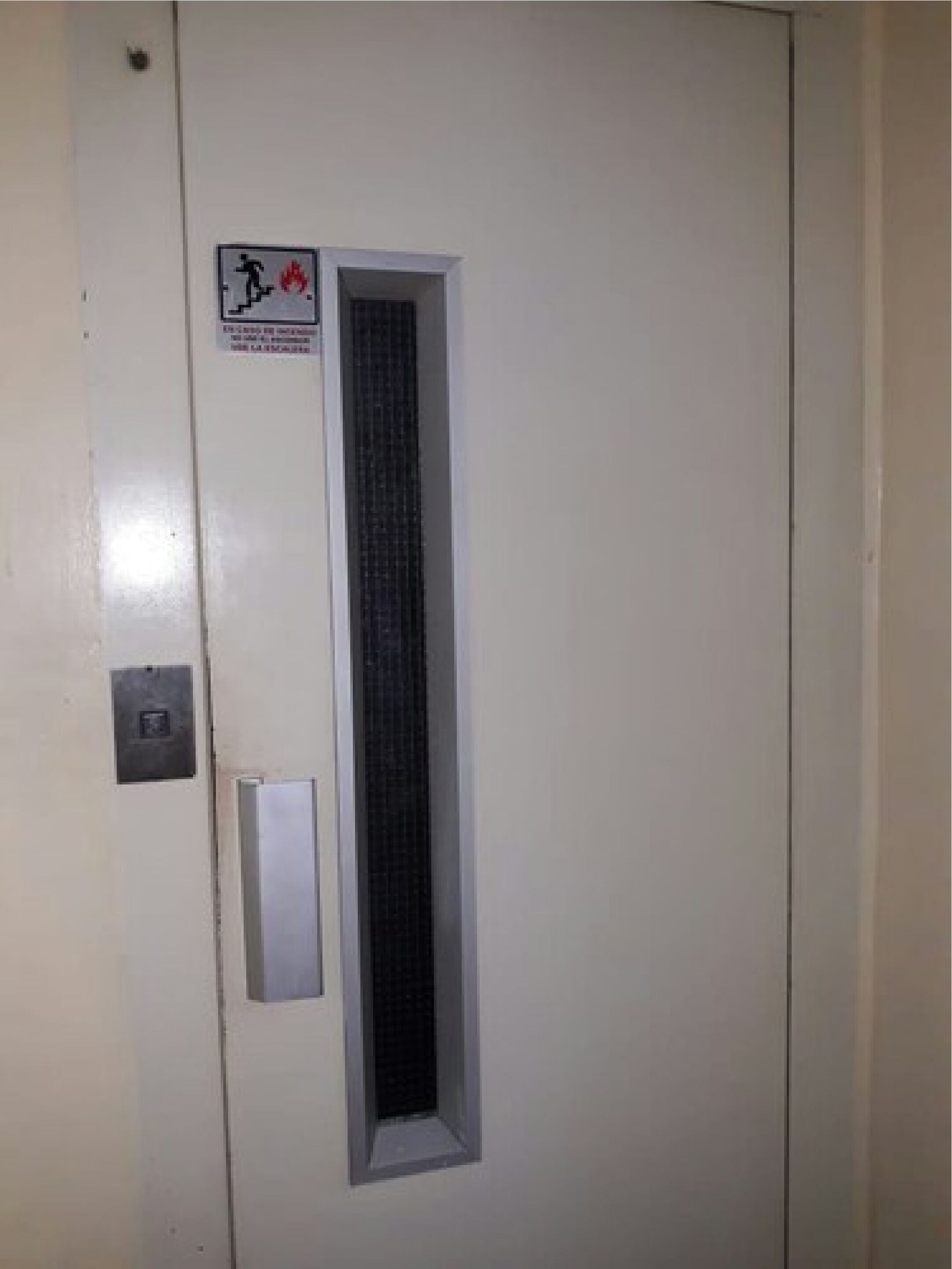 A door with a fire exit sign, a keypad, and a window.