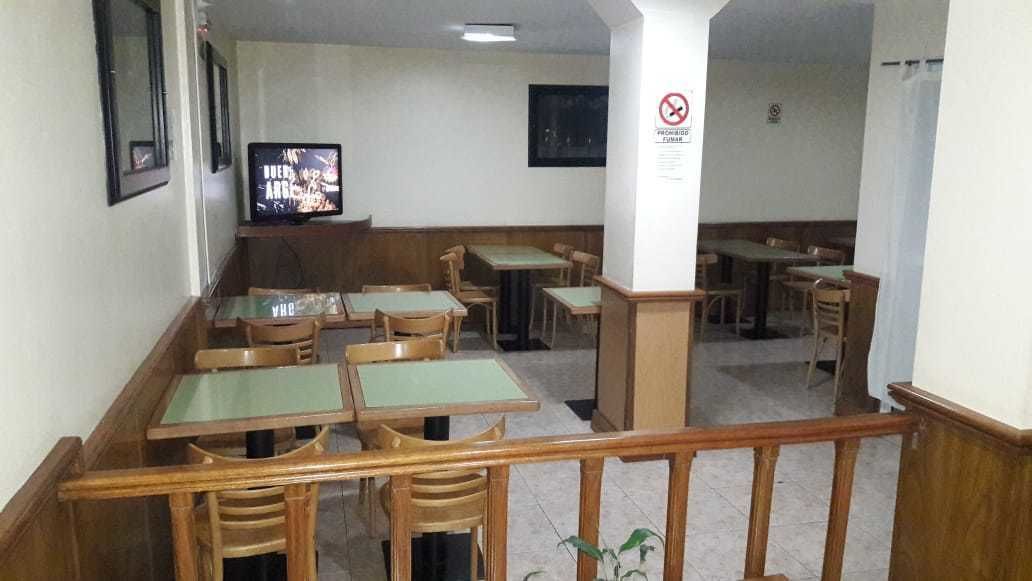 A dining area with wooden tables and chairs, a television on the wall, and a no-smoking sign.