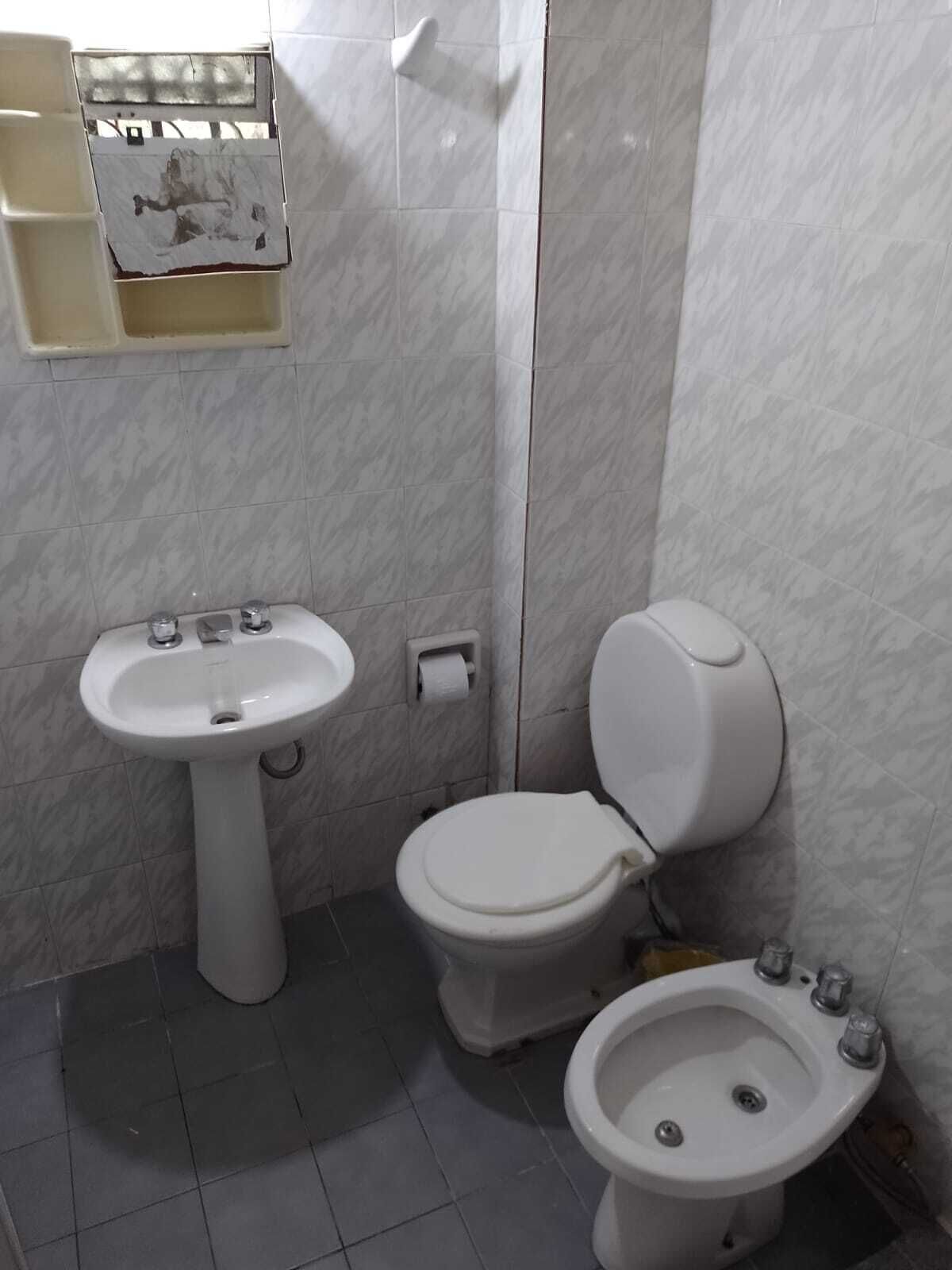 A bathroom with a pedestal sink, a toilet, and a bidet.