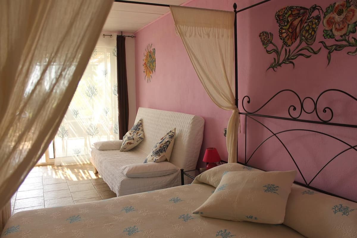 A bedroom with a bed, a chair, and a nightstand.