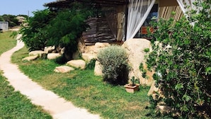 A rustic house with a thatched roof, a visible path leading to the entrance, and a small garden area with rocks and plants. - Brise Marine (Bonifacio)