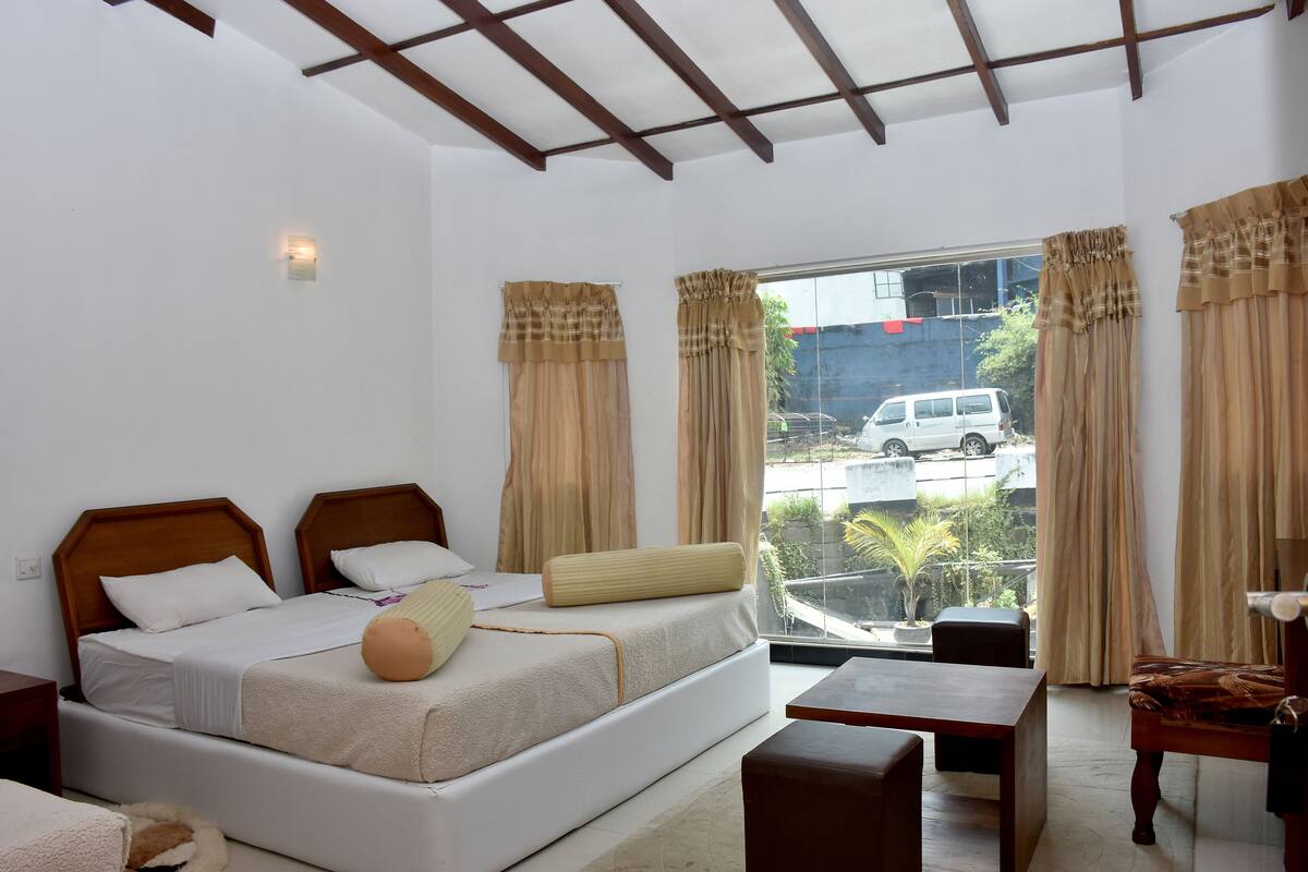 A bedroom with a bed, bedside tables, a window with curtains, and a view of the outside.