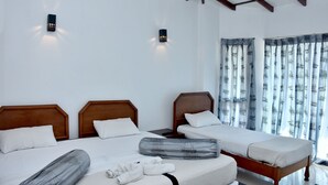 A hotel room with two beds, wooden headboards, white bedding, a grey patterned pillow, a white towel, and a wooden nightstand. - Hotel Hill View (Hatton)