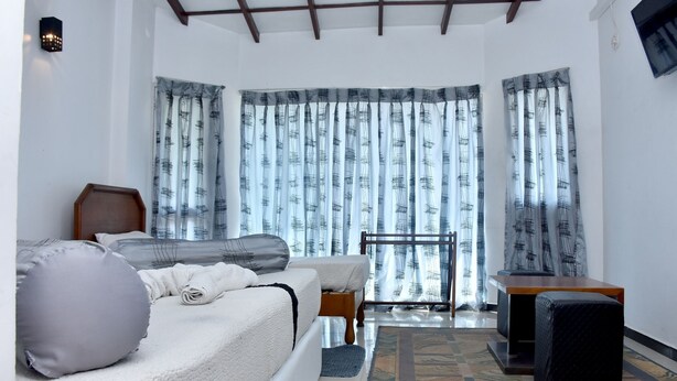 A bedroom with a bed, a desk, and a chair. There are curtains on the windows. - Hotel Hill View (Hatton)