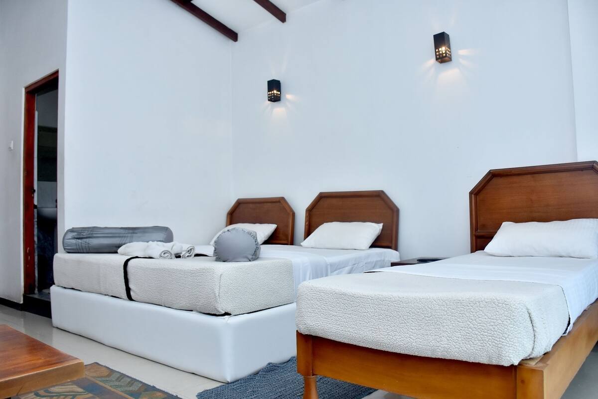 A hotel room with two beds, a sofa, and a wooden floor.