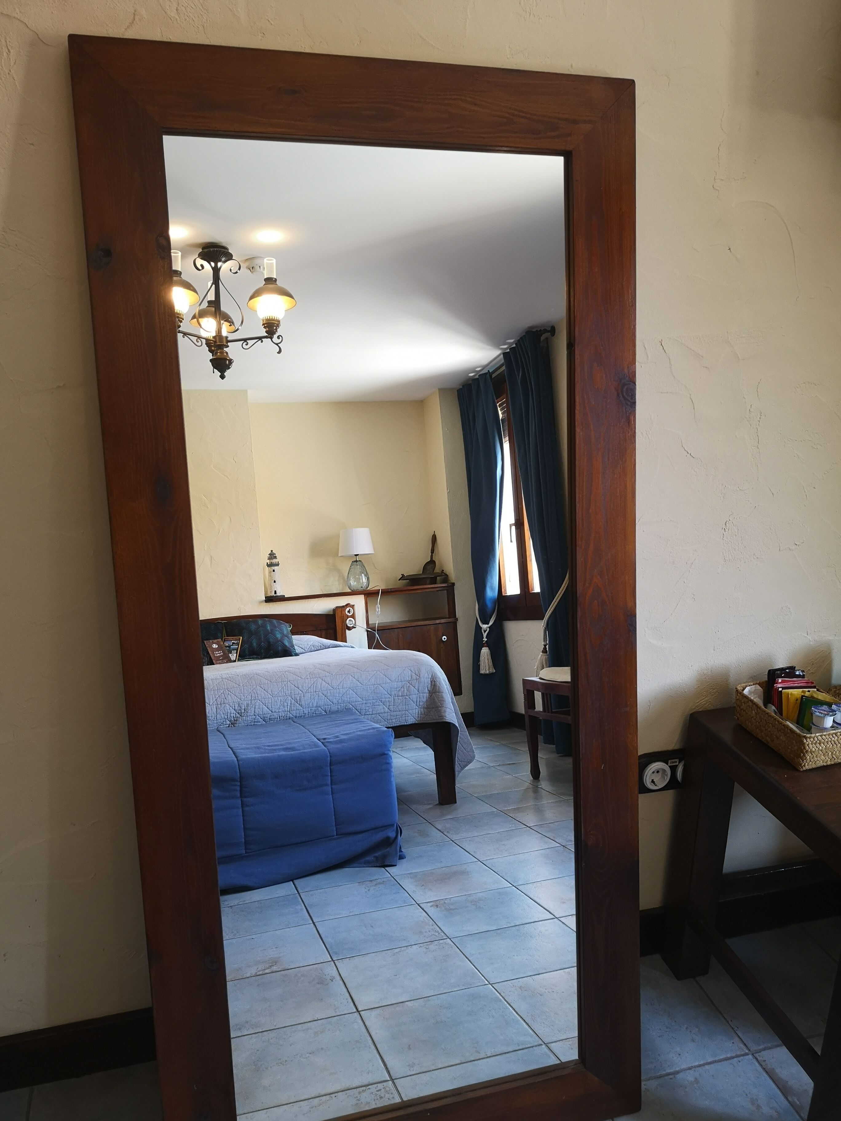Un dormitorio con cama, mesita de noche, lámpara y espejo en la pared.