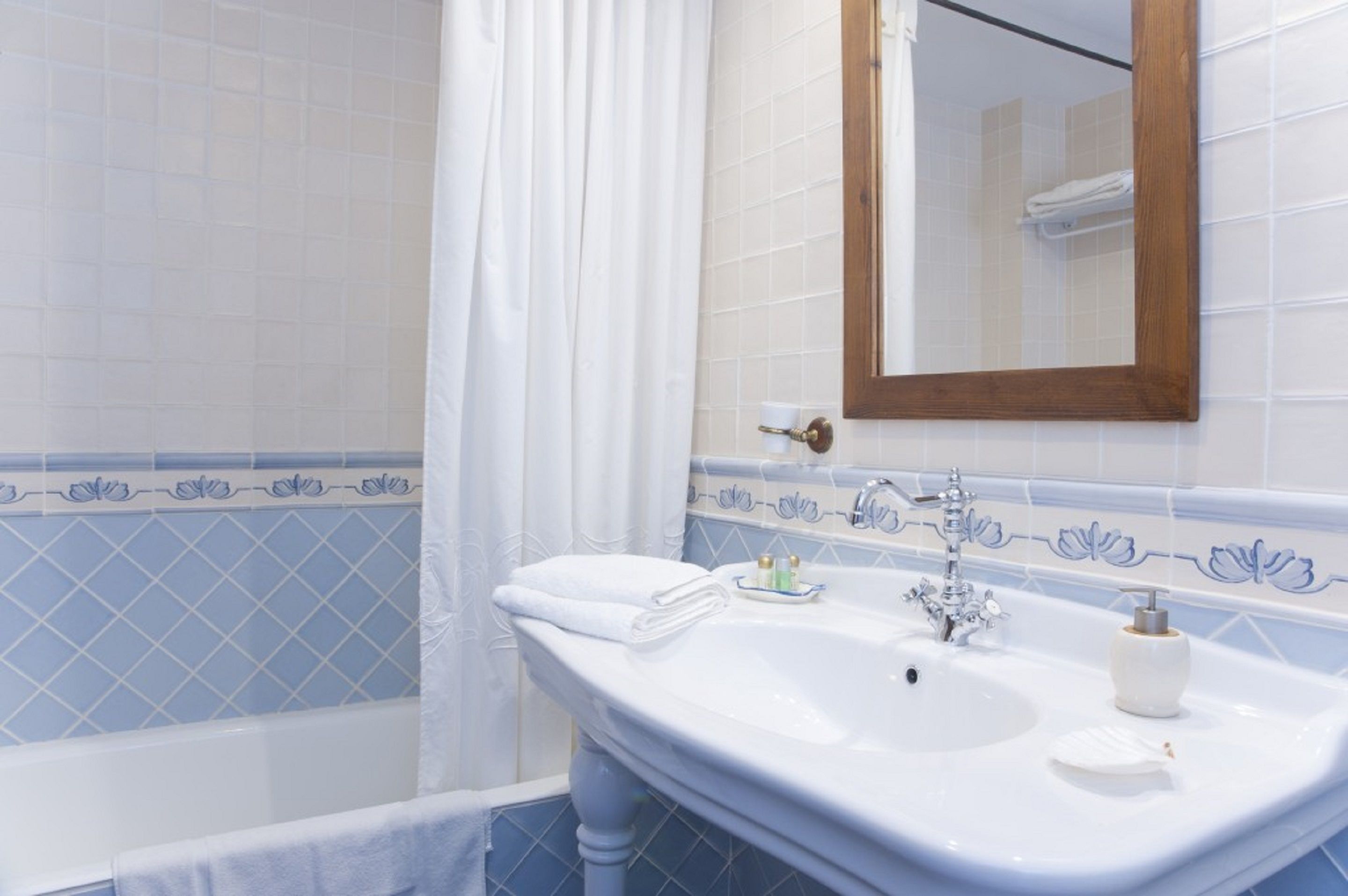 Une salle de bain avec un lavabo blanc, un miroir et une baignoire.