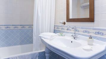 Une salle de bain avec un lavabo blanc, un miroir et une baignoire.