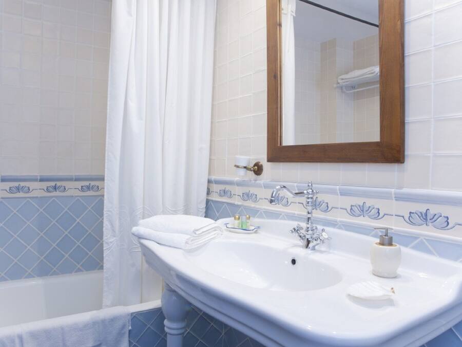 Une salle de bain avec un lavabo blanc, un miroir et une baignoire.